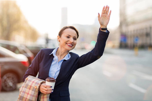 Woman waving for taxi on city street - Foto, Imagem