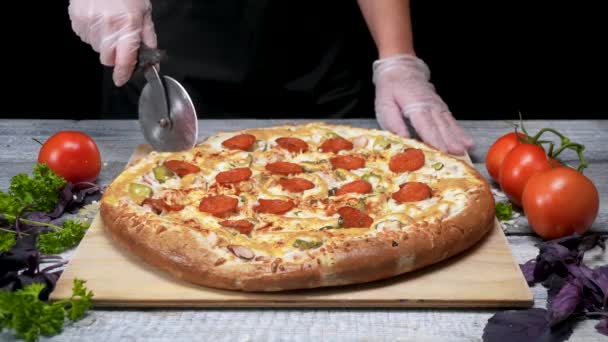 Cook cuts pizza with roller knife. Frame. Chef gloves cut roller knife freshly baked pizza. Cutting delicious pizza before serving - Footage, Video