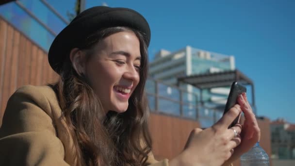 Šťastná brunetka čte SMS a prohlíží si obrázky v smartphone, zblízka - Záběry, video