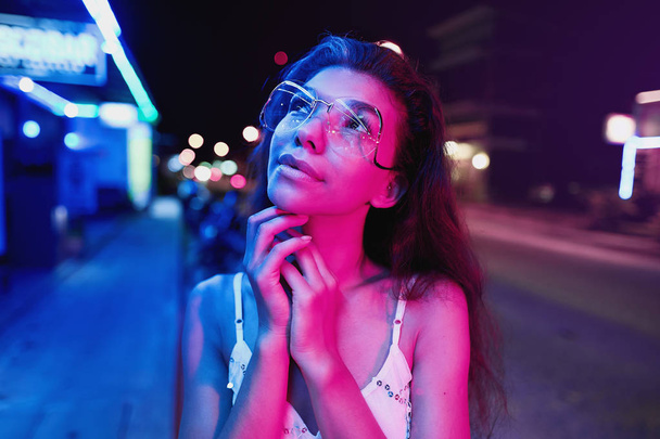 portrait of a beautiful young woman with glasses in futuristic neon light - 写真・画像