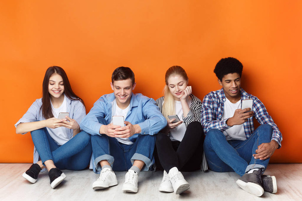 Dépendance au gadget. Adolescents avec smartphones, mur orange
 - Photo, image