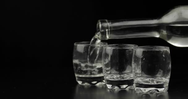 Öntött fel három lövés a vodka egy üveg üvegre. Fekete háttér - Felvétel, videó