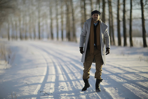 homem na moda em um estilo de casaco / inverno, caminhar contra o pano de fundo da paisagem de inverno, tempo nevado, roupas quentes
 - Foto, Imagem