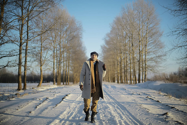 fashionable man in a coat / winter style, walk against the backdrop of the winter landscape, snowy weather, warm clothes - Foto, afbeelding