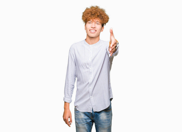 Mladý pohledný obchodní muž s afro vlasy nosí elegantní tričko s úsměvem přátelskou nabídku handshake jako pozdrav a vítání. Úspěšné podnikání. - Fotografie, Obrázek