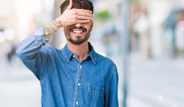 Young handsome man over isolated background smiling and laughing with hand on face covering eyes for surprise. Blind concept. - Foto, afbeelding