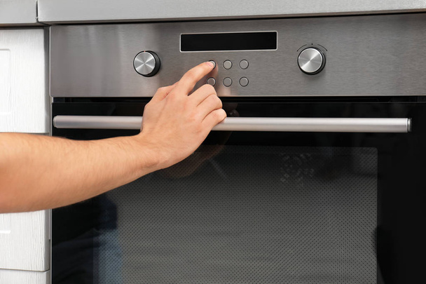 Young man adjusting oven settings in kitchen, closeup - Foto, immagini