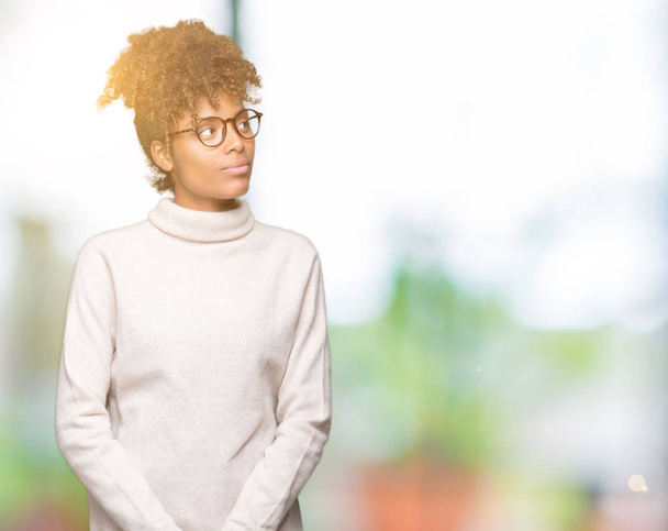 Belle jeune femme afro-américaine portant des lunettes sur fond isolé souriant côté regardant et regardant loin en pensant
. - Photo, image