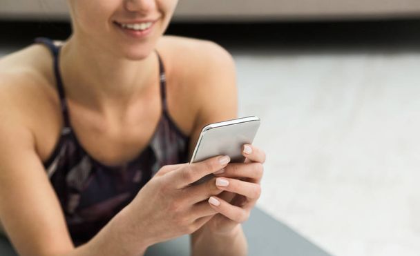 Mujer usando la aplicación de fitness en su teléfono inteligente después del entrenamiento
 - Foto, imagen