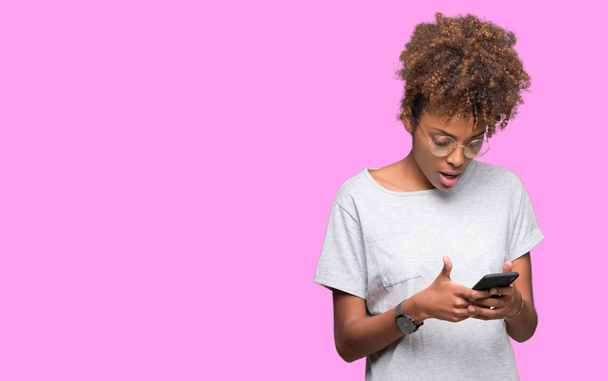 Giovane donna afroamericana utilizzando smartphone su sfondo isolato spaventato in stato di shock con un volto a sorpresa, spaventato ed eccitato con espressione di paura
 - Foto, immagini