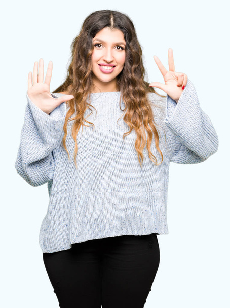 Young beautiful woman wearing winter sweater showing and pointing up with fingers number eight while smiling confident and happy. - Фото, зображення