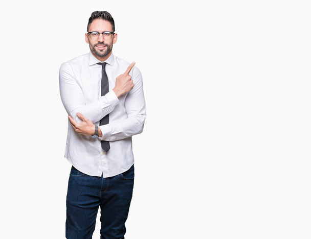 Jonge knappe business man dragen bril over geïsoleerde achtergrond wijzen met de vinger van de hand naar de kant tonen van reclame, serieuze en rustige gezicht - Foto, afbeelding