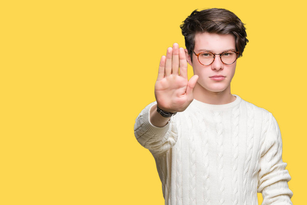 Young handsome man wearing glasses over isolated background doing stop sing with palm of the hand. Warning expression with negative and serious gesture on the face. - Foto, imagen