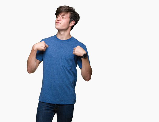 junger gutaussehender Mann, der ein blaues T-Shirt über isoliertem Hintergrund trägt und selbstbewusst mit einem Lächeln im Gesicht aussieht, sich mit stolzen und glücklichen Fingern zeigt. - Foto, Bild