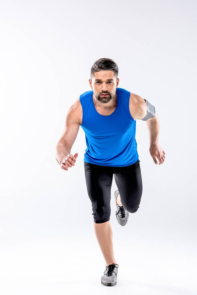 Athletic man in sportswear running and looking at camera on white - Foto, Bild