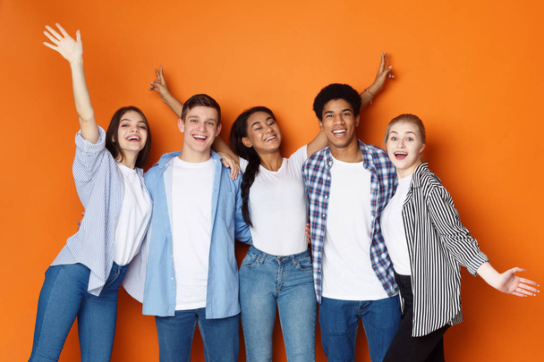 Studenten amüsieren sich über orangefarbenen Studiohintergrund - Foto, Bild