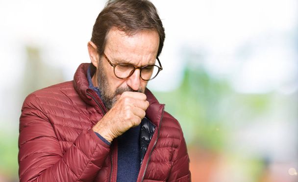 Middle age handsome man wearing glasses and winter coat feeling unwell and coughing as symptom for cold or bronchitis. Healthcare concept. - Photo, Image