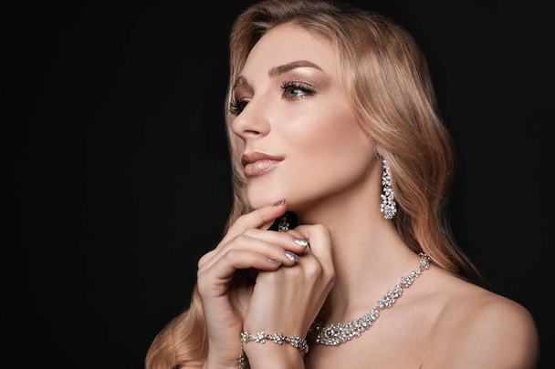 Beautiful young woman with elegant jewelry on dark background. Space for text - Fotoğraf, Görsel