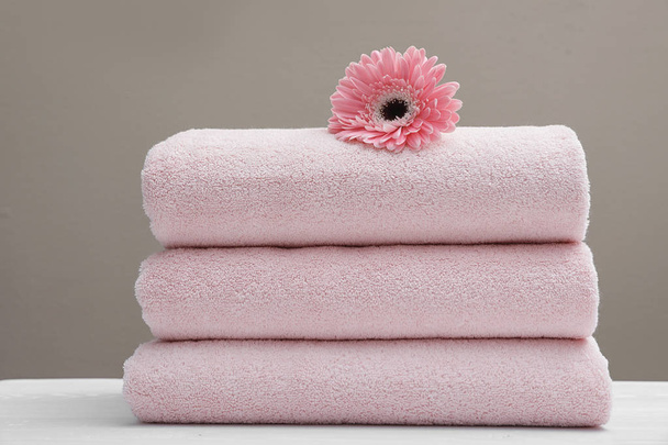 Stack of fresh towels with flower on table - Фото, изображение