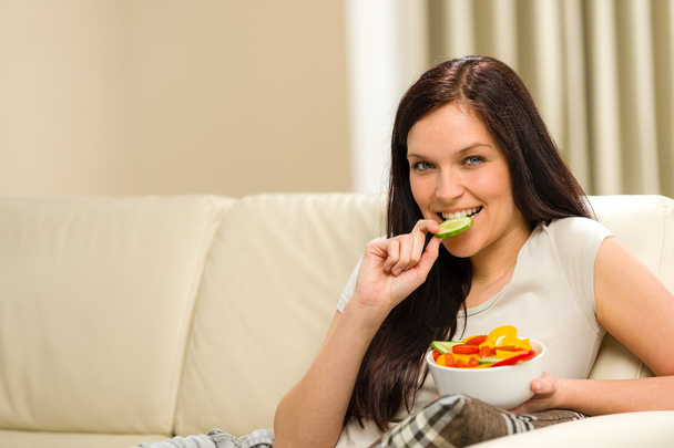 Woman sitting on sofa eating mixed salad - Foto, immagini