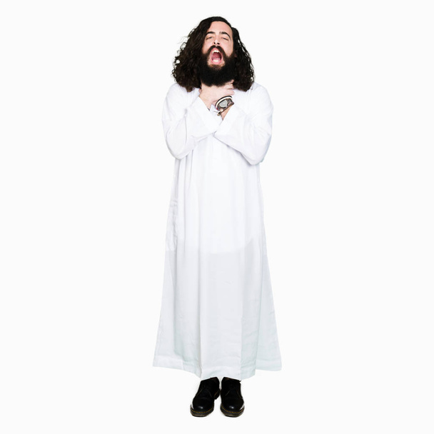 Man wearing Jesus Christ costume shouting and suffocate because painful strangle. Health problem. Asphyxiate and suicide concept. - Photo, Image