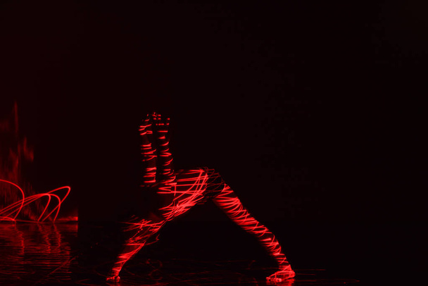 Ballet danseuse dansant devant et lumière rouge tout en exprimant l'enfer avec ses mouvements de danse magnifiques
. - Photo, image