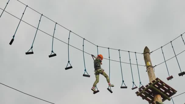 Meisje klimmen in een avonturenpark is plaats die kan bevatten grote verscheidenheid van elementen, zoals touwklimmen oefeningen, hindernisbanen en zip-lijnen. - Video