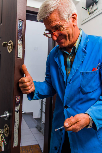 Ouvrier répare la serrure de porte dans le couloir
 - Photo, image