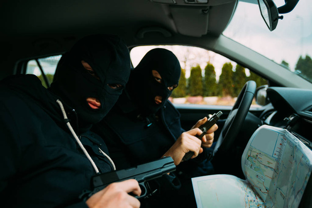 Ladrões de bancos com suas máscaras apontando para o mapa preparado para
 - Foto, Imagem