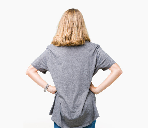 Gyönyörű fiatal nő, fárasztó nagyméretű alkalmi póló, elszigetelt háttérben álló hátra keres el karral a test felett - Fotó, kép