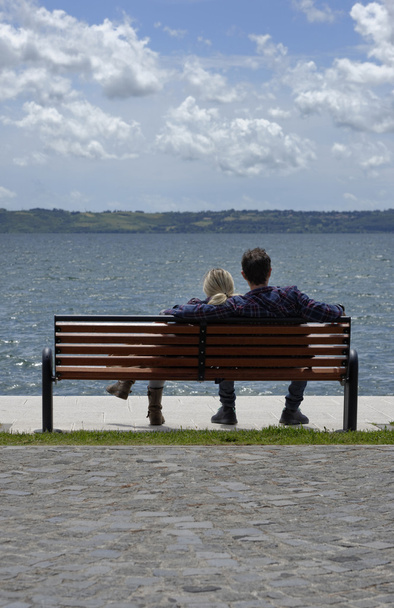 イタリア、ブラッチャーノ湖 - ローマ、若いカップルのベンチでリラックス - 写真・画像