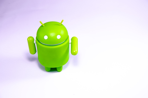 April 2019. Los Angeles,USA. Green plastic Android figure on a white background and with a smartphone. Figure, logo Android, Google - Photo, Image