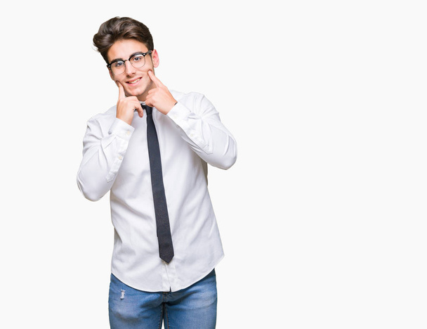 Young business man wearing glasses over isolated background Smiling with open mouth, fingers pointing and forcing cheerful smile - Photo, image