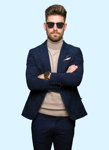 Young handsome elegant man wearing sunglasses skeptic and nervous, disapproving expression on face with crossed arms. Negative person. - Photo, Image