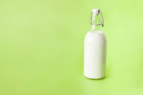milk in a bottle on a green background - Foto, afbeelding