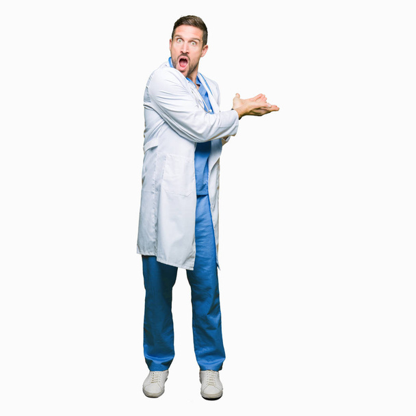 Красивий лікар чоловік в медичній формі над ізольованим тлом Вказуючи на бік рукою і відкритою долонею, представляючи рекламу щасливою і впевненою
 - Фото, зображення