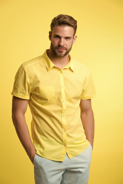 Man on calm face posing confidently with hands in pockets. Man look attractive in casual linen shirt. Guy fashion model wear casual shirt. Feel comfortable in simple outfit. Casual comfortable outfit - Фото, изображение