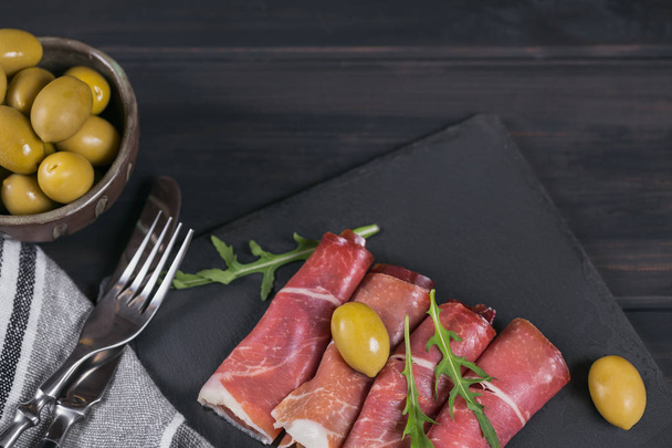 Black stone platter with slices of cured ham or Spanish jamon se - Fotoğraf, Görsel