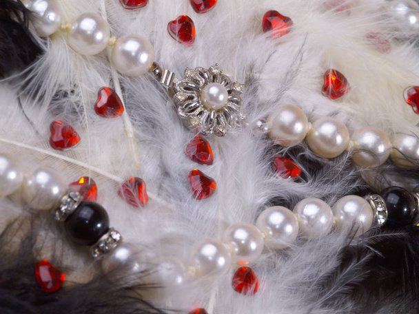 detail of pearl necklace on black and white feathers with strass hearts - Фото, зображення