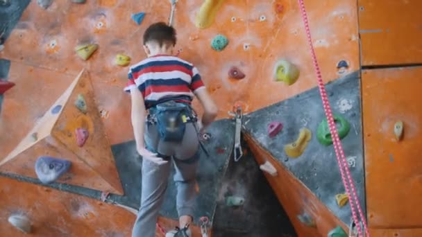 Extreme sport, boulderen. Een tiener jongen klimmen op een rotswand. - Video