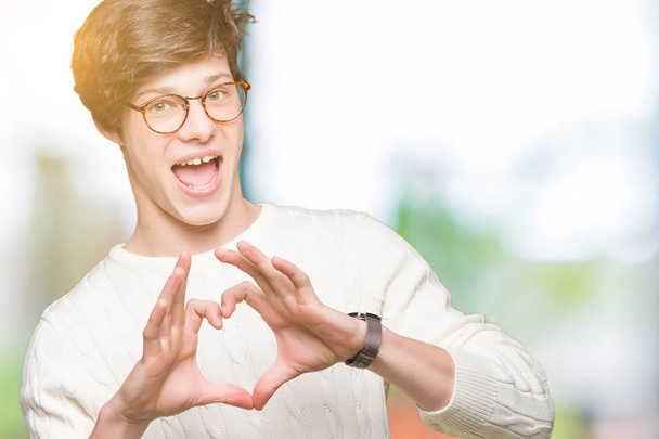 Homem bonito jovem vestindo óculos sobre fundo isolado sorrindo no amor mostrando símbolo do coração e forma com as mãos. Conceito romântico
. - Foto, Imagem