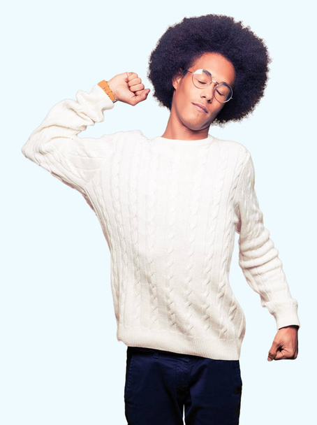 Молодий афроамериканець людиною з афро волосся в окулярах розтягнення назад, втомився і розкуто, сонливість і позіхаючи для раннього ранку - Фото, зображення