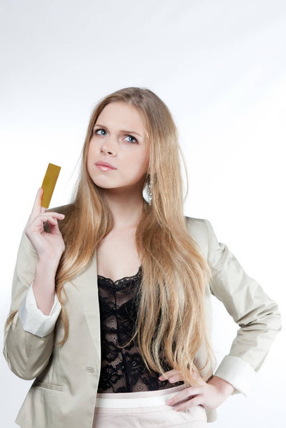 Happy young woman holding a golden credit card on a white background - Φωτογραφία, εικόνα
