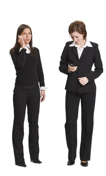 Two businesswomen using mobile phones isolated against a white background. - Valokuva, kuva