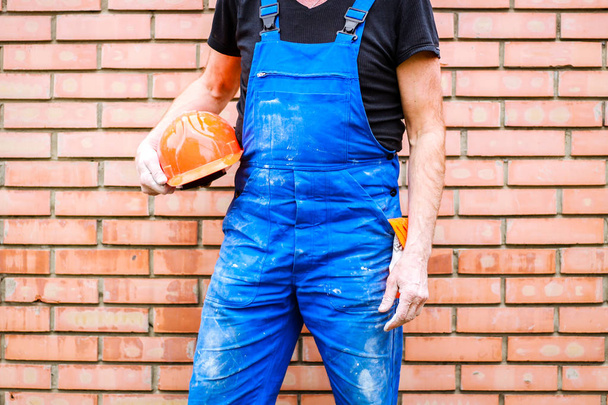 Een bouwer met een bouw beker in zijn handen tegen de ACHTERG - Foto, afbeelding