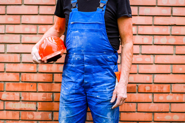 A builder with a construction cup in his hands against the backg - Φωτογραφία, εικόνα