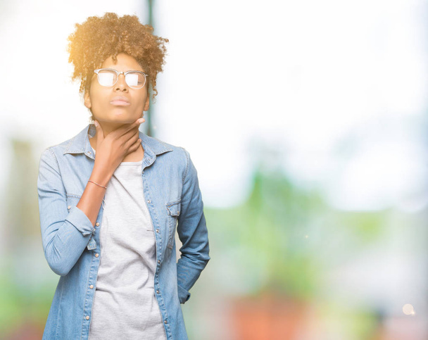 Hermosa mujer afroamericana joven con gafas sobre fondo aislado tocando el cuello doloroso, dolor de garganta para la gripe, la clod y la infección
 - Foto, Imagen