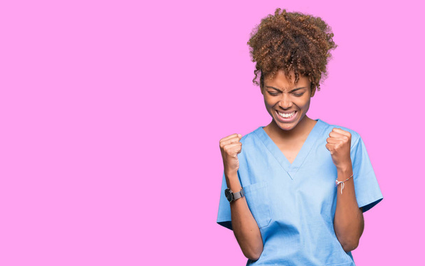 Молодая африканская американка доктор женщина на изолированном фоне очень счастлива и взволнована делая жест победителя с поднятыми руками, улыбаясь и крича об успехе. Концепция празднования
. - Фото, изображение
