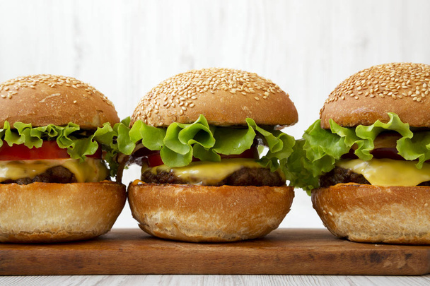 Cheeseburgers caseiros em tábua de madeira rústica, vista lateral. Fechar
- - Foto, Imagem