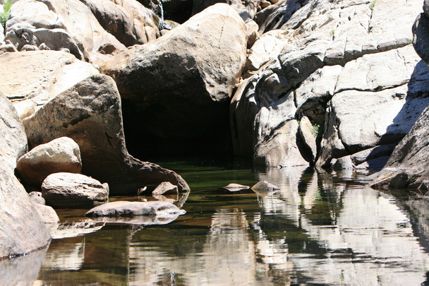 Маленький природный водопад каскадом над скалами в спокойный синий пруд внизу с шелковистой внешностью от длительного воздействия
 - Фото, изображение